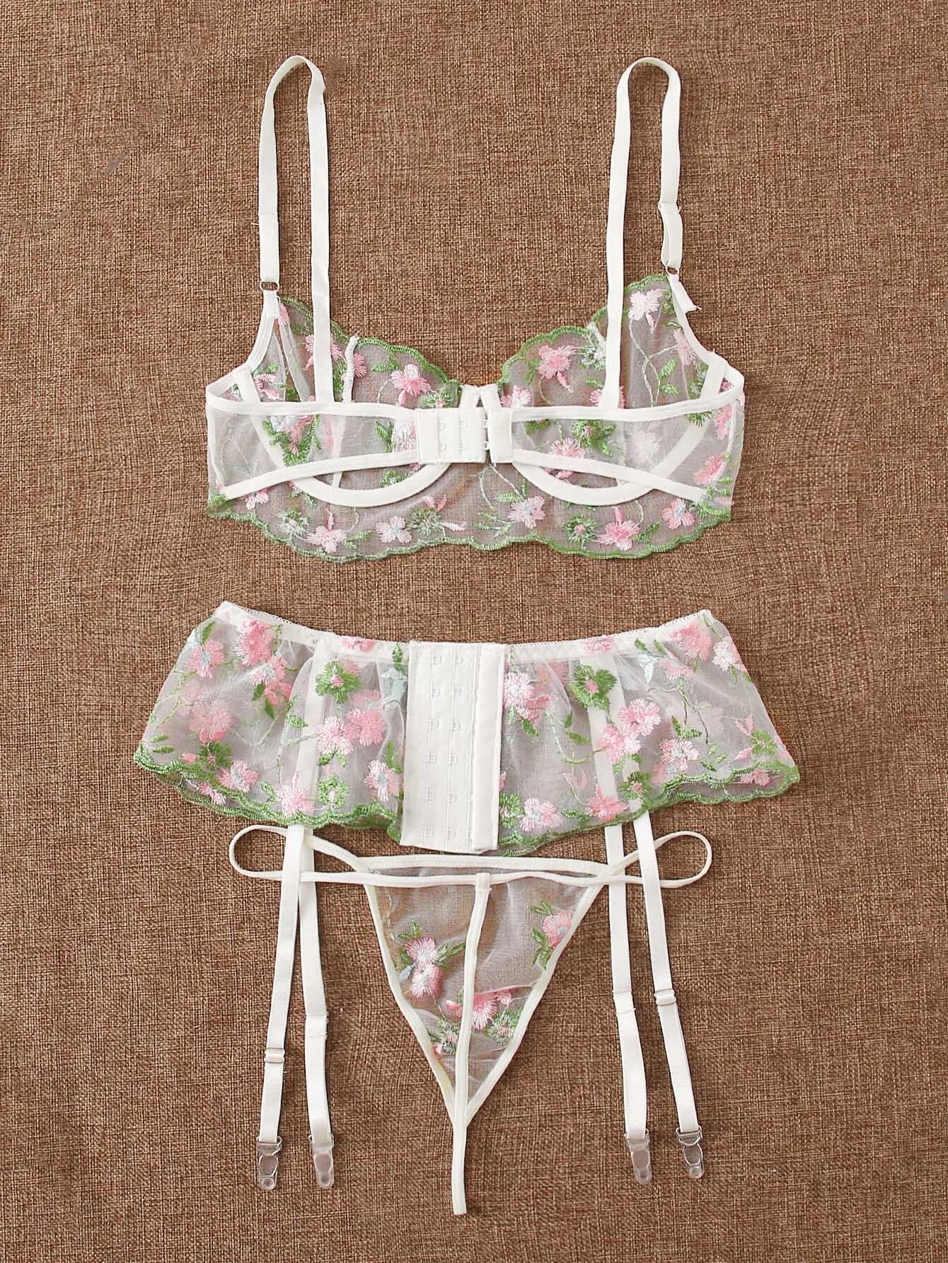 Woman wearing black embroidered mesh lingerie set with bra, thong, and garter belt, front view showing intricate lace detailing