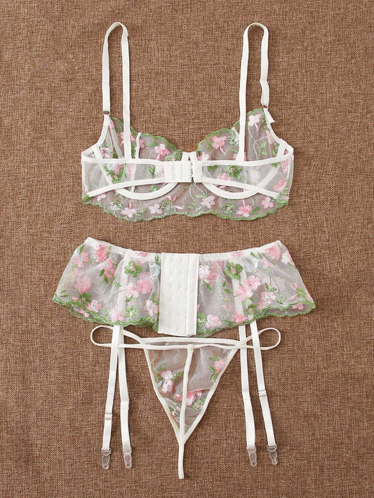 Woman wearing black embroidered mesh lingerie set with bra, thong, and garter belt, front view showing intricate lace detailing